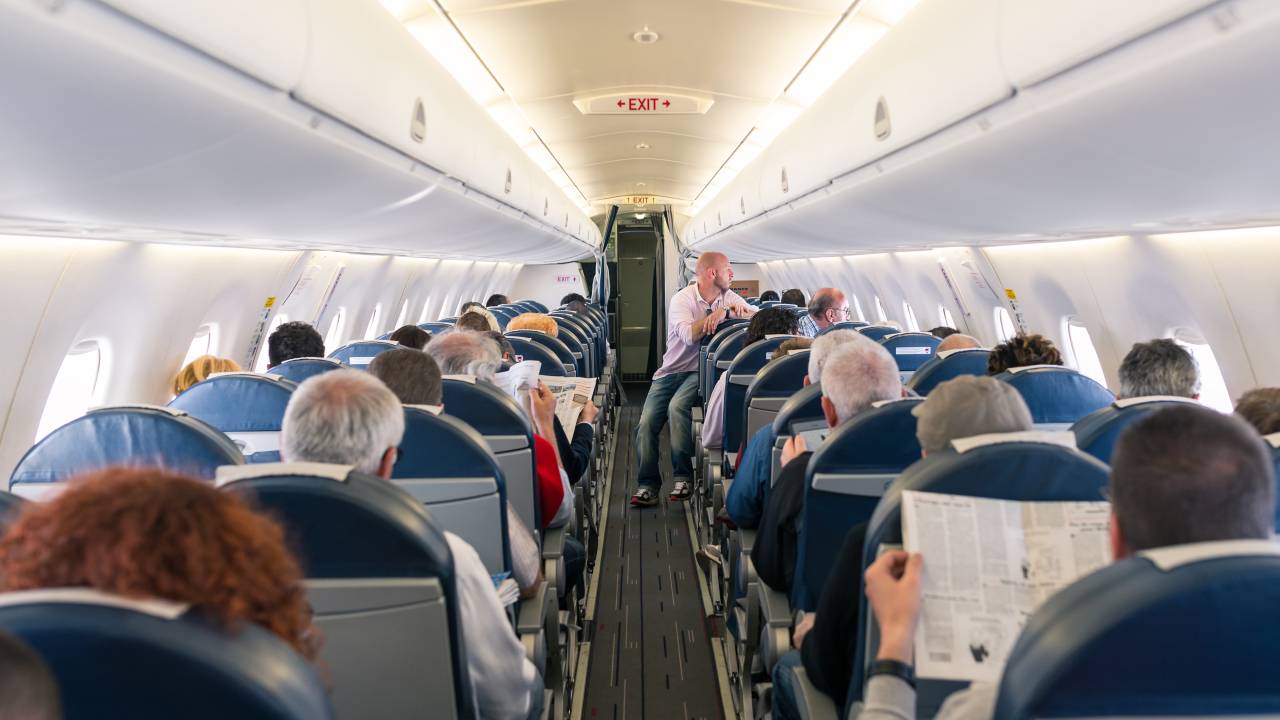 Cabine de um voo comercial de avião da Air France com passageiros a bordo lendo jornal