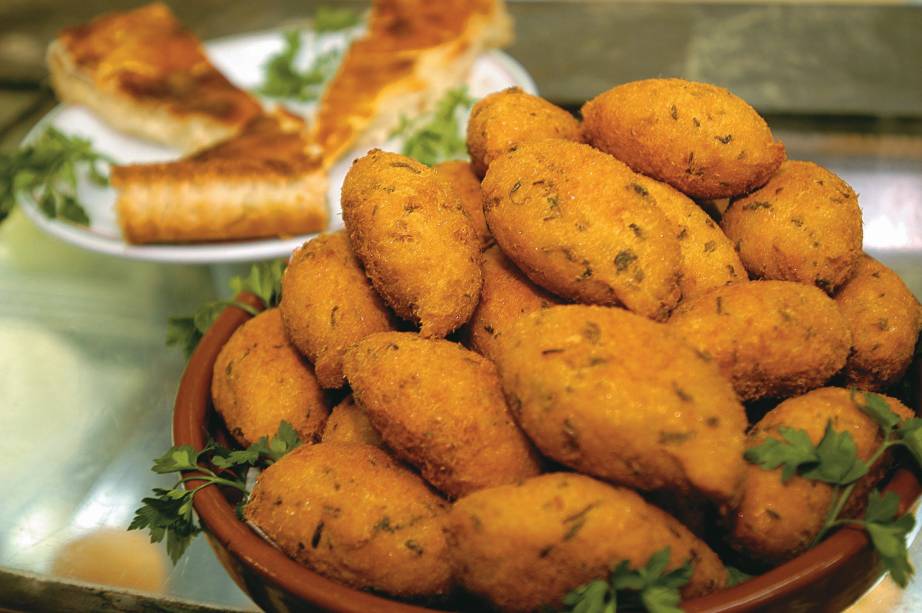 Assim como outros pratos que compõem a ceia brasileira, o <a href="https://mdemulher.abril.com.br/receitas/bolinho-de-bacalhau/" target="_blank" rel="noopener">bolinho de bacalhau</a> tem sua origem atrelada aos colonizadores da América. Neste caso, os portugueses. Considerado uma das heranças da culinária mediterrânea, o petisco já era consumido em larga escala há pelo menos dois séculos atrás. Feito com batata e lascas do peixe, que é fartamente encontrado nos mares da região, o bolinho teve sua primeira versão oficial documentada em 1904, no livro <em>Tratado de Cozinha e Copa</em>, escrito pelo oficial português Carlos Bandeira de Melo, que adotava o pseudônimo de Carlos Bento de Maia. <a href="https://mdemulher.abril.com.br/receitas/bolinho-de-bacalhau/" target="_blank" rel="noopener"><strong>Veja aqui uma receita de bolinho de bacalhau</strong></a> Assim como outros pratos que compõem a ceia brasileira, o <a href="https://mdemulher.abril.com.br/receitas/bolinho-de-bacalhau/" target="_blank" rel="noopener">bolinho de bacalhau</a> tem sua origem atrelada aos colonizadores da América. Neste caso, os portugueses. Considerado uma das heranças da culinária mediterrânea, o petisco já era consumido em larga escala há pelo menos dois séculos atrás. Feito com batata e lascas do peixe, que é fartamente encontrado nos mares da região, o bolinho teve sua primeira versão oficial documentada em 1904, no livro <em>Tratado de Cozinha e Copa</em>, escrito pelo oficial português Carlos Bandeira de Melo, que adotava o pseudônimo de Carlos Bento de Maia. <a href="https://mdemulher.abril.com.br/receitas/bolinho-de-bacalhau/" target="_blank" rel="noopener"><strong>Veja aqui uma receita de bolinho de bacalhau</strong></a>