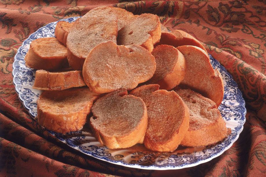 A receita feita com pães, leite e ovos foi criada para recuperar mulheres após o parto. Natural da península ibérica, o doce foi caindo no gosto do povo aos poucos, sendo que no começo do século 20 se tornou um alimento comum nas tabernas de Madri, na Espanha. Acompanhado de vinho, a <a href="https://mdemulher.abril.com.br/gastronomia/7-receitas-de-rabanada-para-voce-arrasar-no-doce-mais-tradicional-do-natal/" target="_blank" rel="noopener">rabanada</a> também é muito associada aos períodos religiosos, como a quaresma, talvez pela falta de carne no cardápio. Seus primeiros registros históricos são datados do século 14, em Portugal, e foram feitos pelo poeta espanhol Juan del Encina. Já a primeira receita documentada pertence ao livro de Francisco Martinez Montiño, servidor da Coroa Real da Espanha no período. <strong><a href="https://mdemulher.abril.com.br/gastronomia/7-receitas-de-rabanada-para-voce-arrasar-no-doce-mais-tradicional-do-natal/" target="_blank" rel="noopener">Veja aqui receitas de rabanada</a></strong>