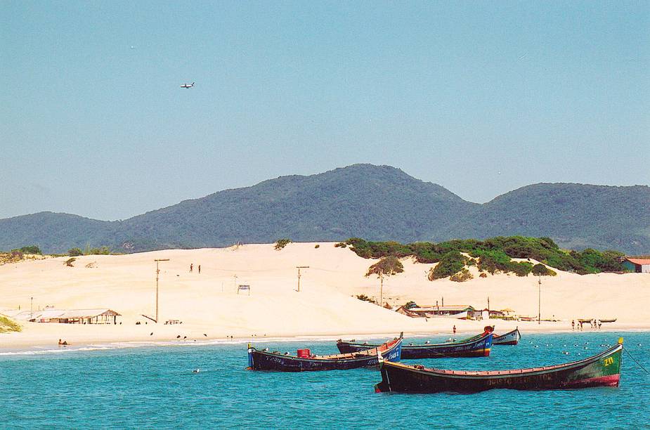 As praias mais selvagens e sossegadas ficam no sul da ilha. São tantas praias que nem todas têm nome. Como se não as bastasse, Floripa também agrada com suas lagoas, dunas, montanhas e mangues. <a href="https://www.booking.com/searchresults.pt-br.html?aid=332455&lang=pt-br&sid=eedbe6de09e709d664615ac6f1b39a5d&sb=1&src=searchresults&src_elem=sb&error_url=https%3A%2F%2Fwww.booking.com%2Fsearchresults.pt-br.html%3Faid%3D332455%3Bsid%3Deedbe6de09e709d664615ac6f1b39a5d%3Bcity%3D-633693%3Bclass_interval%3D1%3Bdest_id%3D-634523%3Bdest_type%3Dcity%3Bdtdisc%3D0%3Bfrom_sf%3D1%3Bgroup_adults%3D2%3Bgroup_children%3D0%3Binac%3D0%3Bindex_postcard%3D0%3Blabel_click%3Dundef%3Bno_rooms%3D1%3Boffset%3D0%3Bpostcard%3D0%3Braw_dest_type%3Dcity%3Broom1%3DA%252CA%3Bsb_price_type%3Dtotal%3Bsearch_selected%3D1%3Bsrc%3Dsearchresults%3Bsrc_elem%3Dsb%3Bss%3DCanela%252C%2520%25E2%2580%258BRio%2520Grande%2520do%2520Sul%252C%2520%25E2%2580%258BBrasil%3Bss_all%3D0%3Bss_raw%3DCanela%3Bssb%3Dempty%3Bsshis%3D0%3Bssne_untouched%3DCambar%25C3%25A1%26%3B&ss=Florian%C3%B3polis%2C+%E2%80%8BSanta+Catarina%2C+%E2%80%8BBrasil&ssne=Canela&ssne_untouched=Canela&city=-634523&checkin_monthday=&checkin_month=&checkin_year=&checkout_monthday=&checkout_month=&checkout_year=&no_rooms=1&group_adults=2&group_children=0&highlighted_hotels=&from_sf=1&ss_raw=Florian%C3%B3polis&ac_position=0&ac_langcode=xb&dest_id=-643337&dest_type=city&search_pageview_id=91cd738843c90212&search_selected=true&search_pageview_id=91cd738843c90212&ac_suggestion_list_length=5&ac_suggestion_theme_list_length=0" target="_blank" rel="noopener"><em>Busque hospedagens em Florianópolis</em></a>