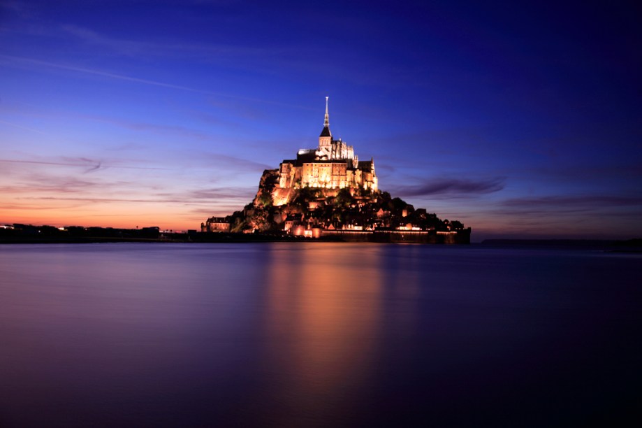 À noite, as luzes acesas no castelo gótico e na muralha do Monte Saint-Michel, na Costa da Normandia, causam um estado de quase hipnose