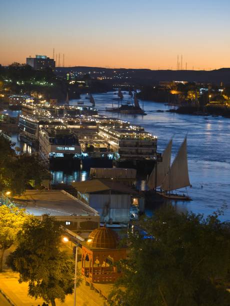 Pôr-do-sol em Aswan, com feluccas e dahabiyas, embarcações de cruzeiro, ancoradas ao longo do rio Nilo