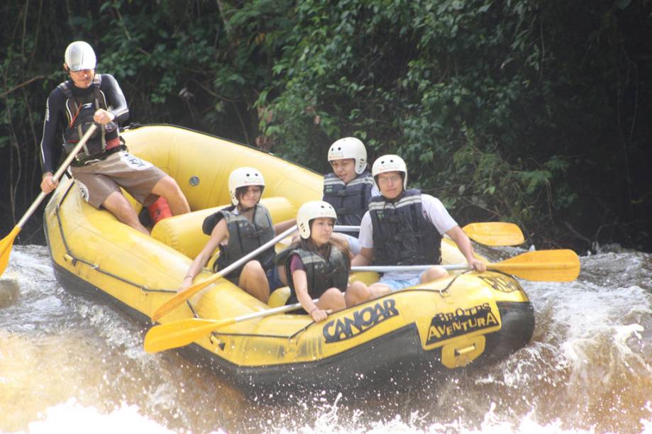 Jovens praticando rafting com monitor da Canoar, no Acampamento Fazenda Estância Peraltas.