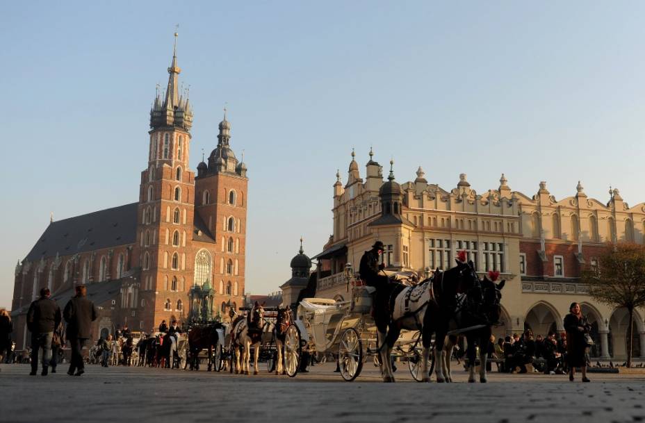 A Praça do Mercado da <a href="https://viajeaqui.abril.com.br/cidades/polonia-cracovia" rel="Cracóvia " target="_blank"><strong>Cracóvia </strong></a>apresenta a decorada Basílica de Santa Maria (à esquerda) e o Grande Salão das Guildas (à direita), onde hoje se encontram variadas lojas de suvenires. A cidade não sediará nenhuma partida da <strong>Eurocopa 2012</strong>, mas certamente vale uma visita, tanto por sua história – ela é declarada <strong>Patrimônio da Humanidade </strong>pela Unesco –, como pela memória sempre presente do falecido papa João Paulo II