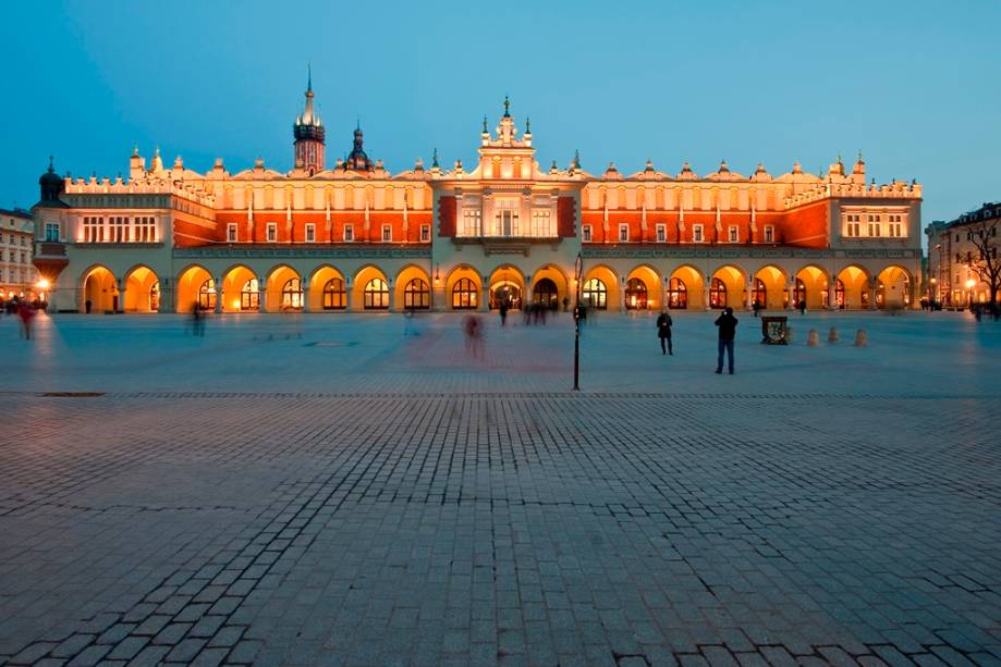 <strong>Praça do Mercado (Rynek Glówny) – <a href="https://beta-develop.viagemeturismo.abril.com.br/cidades/cracovia/" target="_blank" rel="noopener">Cracóvia</a> – <a href="https://beta-develop.viagemeturismo.abril.com.br/paises/polonia-2/" target="_blank" rel="noopener">Polônia</a></strong> O ponto focal de Cracóvia é sua grande Praça do Mercado. Em seu entorno encontram-se algumas das melhores opções de hospedagem da cidade, além de ótimos restaurantes, cafés e bares. Além disso, aqui estão o Sukiennice (Grande Salão das Guildas), à direita, onde hoje os turistas podem adquirir lembranças variadas, e a colorida e ricamente decorada Basílica de Santa Maria. Esta é a maior praça da Europa, declarada Patrimônio da Humanidade pela Unesco <em><a href="https://www.booking.com/searchresults.pt-br.html?aid=332455&sid=d98f25c4d6d5f89238aebe98e11a09ba&sb=1&src=searchresults&src_elem=sb&error_url=https%3A%2F%2Fwww.booking.com%2Fsearchresults.pt-br.html%3Faid%3D332455%3Bsid%3Dd98f25c4d6d5f89238aebe98e11a09ba%3Btmpl%3Dsearchresults%3Bac_click_type%3Db%3Bac_position%3D0%3Bcity%3D-129709%3Bclass_interval%3D1%3Bdest_id%3D-345275%3Bdest_type%3Dcity%3Bdtdisc%3D0%3Bfrom_sf%3D1%3Bgroup_adults%3D2%3Bgroup_children%3D0%3Biata%3DCUZ%3Binac%3D0%3Bindex_postcard%3D0%3Blabel_click%3Dundef%3Bno_rooms%3D1%3Boffset%3D0%3Bpostcard%3D0%3Braw_dest_type%3Dcity%3Broom1%3DA%252CA%3Bsb_price_type%3Dtotal%3Bsearch_selected%3D1%3Bshw_aparth%3D1%3Bslp_r_match%3D0%3Bsrc%3Dsearchresults%3Bsrc_elem%3Dsb%3Bsrpvid%3D18f97cc4163f00ab%3Bss%3DCusco%252C%2520Cusco%252C%2520Peru%3Bss_all%3D0%3Bss_raw%3Dcusco%3Bssb%3Dempty%3Bsshis%3D0%3Bssne%3DSiena%3Bssne_untouched%3DSiena%26%3B&ss=Crac%C3%B3via%2C+Lesser+Poland%2C+Pol%C3%B4nia&is_ski_area=&ssne=Cusco&ssne_untouched=Cusco&city=-345275&checkin_year=&checkin_month=&checkout_year=&checkout_month=&group_adults=2&group_children=0&no_rooms=1&from_sf=1&ss_raw=crac%C3%B3via&ac_position=0&ac_langcode=xb&ac_click_type=b&dest_id=-510625&dest_type=city&iata=KRK&place_id_lat=50.063&place_id_lon=19.937&search_pageview_id=18f97cc4163f00ab&search_selected=true&search_pageview_id=18f97cc4163f00ab&ac_suggestion_list_length=5&ac_suggestion_theme_list_length=0" target="_blank" rel="noopener">Busque hospedagem em Cracóvia</a> </em>