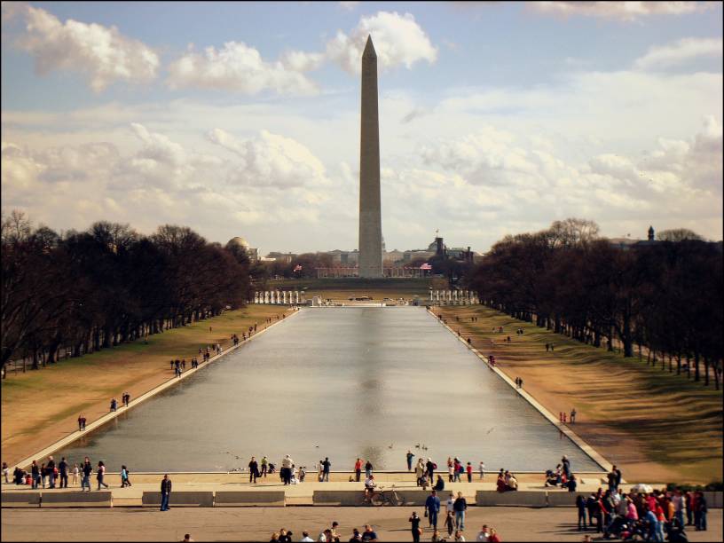 O <strong>Obelisco</strong> da vida real, cercado de visitantes numa tarde ensolarada e tranquila