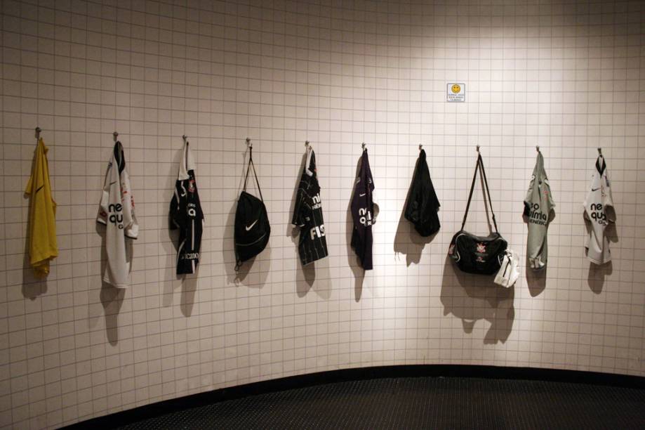 A primeira sala do <strong>Memorial do Corinthians</strong> é a réplica de um vestiário. Camisas penduradas na parede, um saco de bolas no chão, armários com chuteiras e shorts. Ao som do grito da torcida, você se sente como se fosse um jogador profissional prestes a entrar em campo 