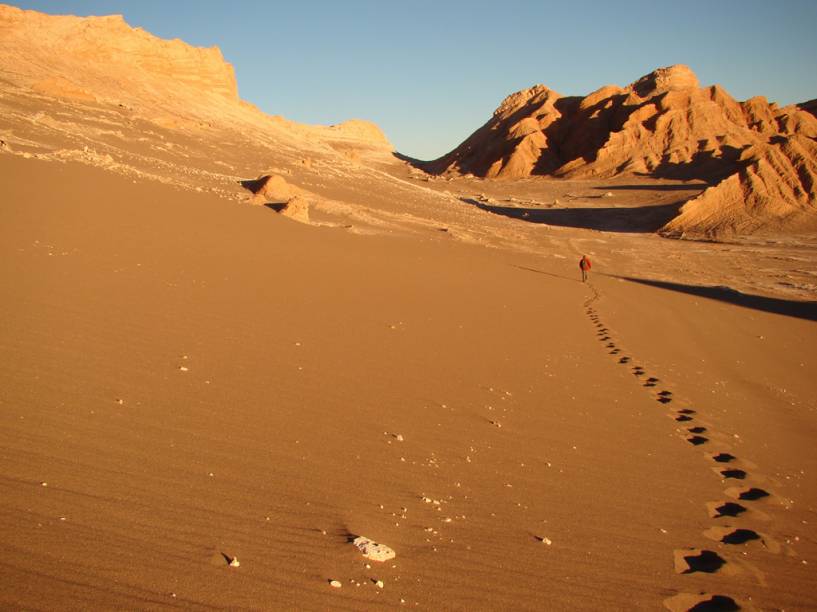 A caminhada pelo <a href="https://viajeaqui.abril.com.br/estabelecimentos/chile-san-pedro-de-atacama-atracao-valle-de-la-luna-e-valle-de-la-muerte" rel="Valle de la Luna" target="_blank"><strong>Valle de la Luna</strong></a> atravessa dunas gigantes e montanhas rochosas em meio a um silêncio quase absoluto, cortado apenas pelo vento e pelos passos na areia. A maioria dos passeios acontece no pôr-do-sol, quando as temperaturas são mais amenas – durante o dia pode passar dos 50ºC