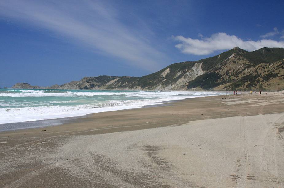 O mar esverdeado da baía Tokomaru forma um belo contraste com a areia escura O mar esverdeado da baía Tokomaru forma um belo contraste com a areia escura