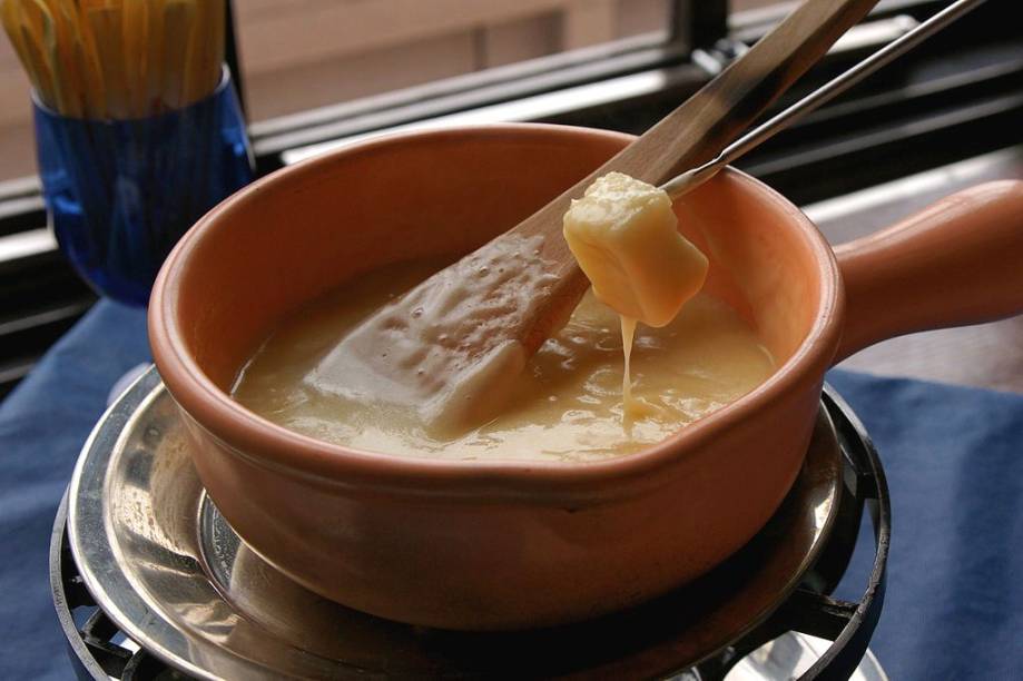 <strong>Fondue, <a href="https://viajeaqui.abril.com.br/paises/suica" rel="Suíça" target="_blank">Suíça</a></strong><br />  Prato nacional da Suíça, a fondue é uma das mais lúdicas experiências gastronômicas que existem. É só o tempo esfriar um pouquinho para os restaurantes de <a href="https://viajeaqui.abril.com.br/cidades/br-rs-gramado" rel="Gramado" target="_blank">Gramado (RS)</a>, <a href="https://viajeaqui.abril.com.br/cidades/br-rj-nova-friburgo" rel="Nova Friburgo" target="_blank">Nova Friburgo (RJ)</a> e <a href="https://viajeaqui.abril.com.br/cidades/br-sp-campos-do-jordao" rel="Campos do Jordão" target="_blank">Campos do Jordão (SP)</a> lotarem com famílias e amigos, todos mergulhando seus espetinhos no <em>rechaud</em>. A mistura cremosa pode levar vários tipos de queijo, como o gruyére e o ementhal, quase sempre perfumados com um pouco de vinho branco e <em>kirsch</em>, um destilado de cereja. Apesar do imaginário popular remeter sua origem às montanhas alpinas, o conceito de queijo derretido provavelmente originou-se em algum restaurante urbano. Menos romântico, mais provável. Seja como for, é uma pequena e alegre celebração coletiva