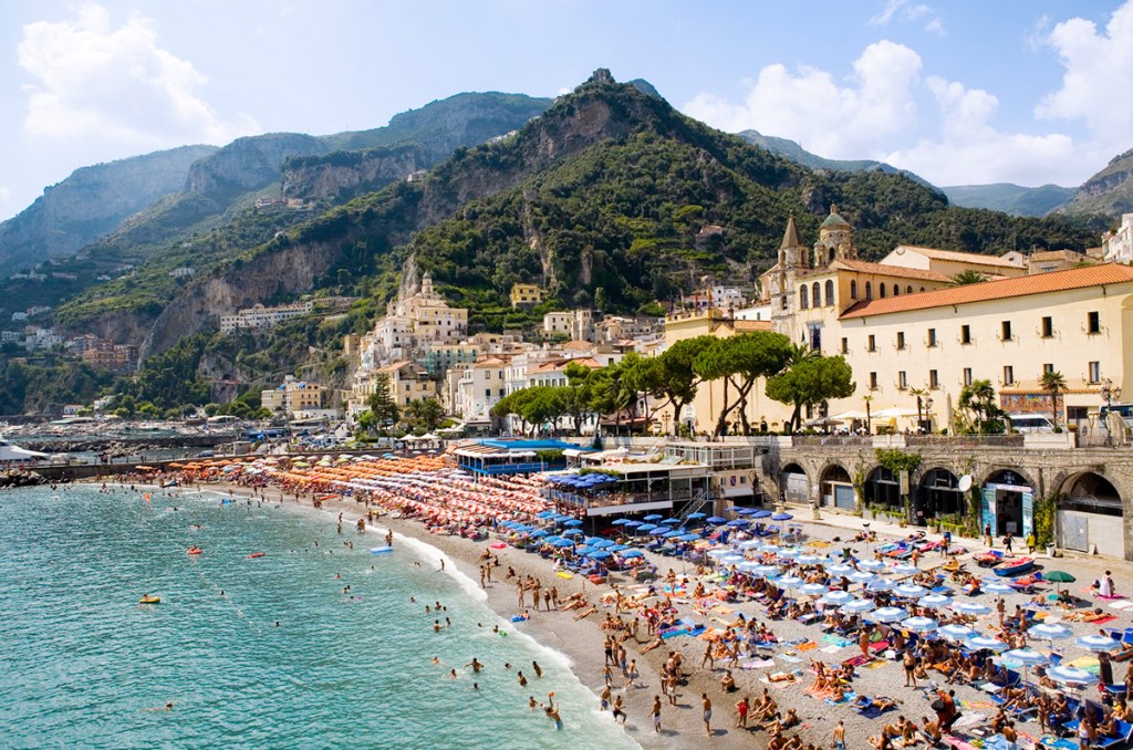 <strong><a href="https://viajeaqui.abril.com.br/cidades/italia-costa-amalfitana" rel="Costa Amalfitana" target="_self">Costa Amalfitana</a>, <a href="https://viajeaqui.abril.com.br/paises/italia" rel="It&aacute;lia" target="_self">It&aacute;lia</a></strong>                Destino rom&acirc;ntico n&uacute;mero um da It&aacute;lia, e tombado como Patrim&ocirc;nio Mundial da Humanidade pela UNESCO. S&oacute; isso j&aacute; &eacute; um grande motivo para visitar a regi&atilde;o, localizada ao sul de N&aacute;poles, com suas estradinhas lindas e vis&otilde;es espetaculares de um mar extremamente azul. Suas principais cidades s&atilde;o <strong>Amalfi (foto)</strong>, Positano e Ravello. Na primeira, mais bem estruturada para receber os turistas, um dos grandes destaques &eacute; a Grotta dello Smeraldo, com &aacute;guas que refletem tons de verde esmeralda                <em><a href="https://www.booking.com/city/it/amalfi.pt-br.html?sid=5b28d827ef00573fdd3b49a282e323ef;dcid=1?aid=332455&label=viagemabril-as-mais-belas-praias-do-mediterraneo" rel="Veja pre&ccedil;os de hot&eacute;is em Amalfi no Booking.com" target="_blank">Veja pre&ccedil;os de hot&eacute;is em Amalfi no Booking.com</a></em>