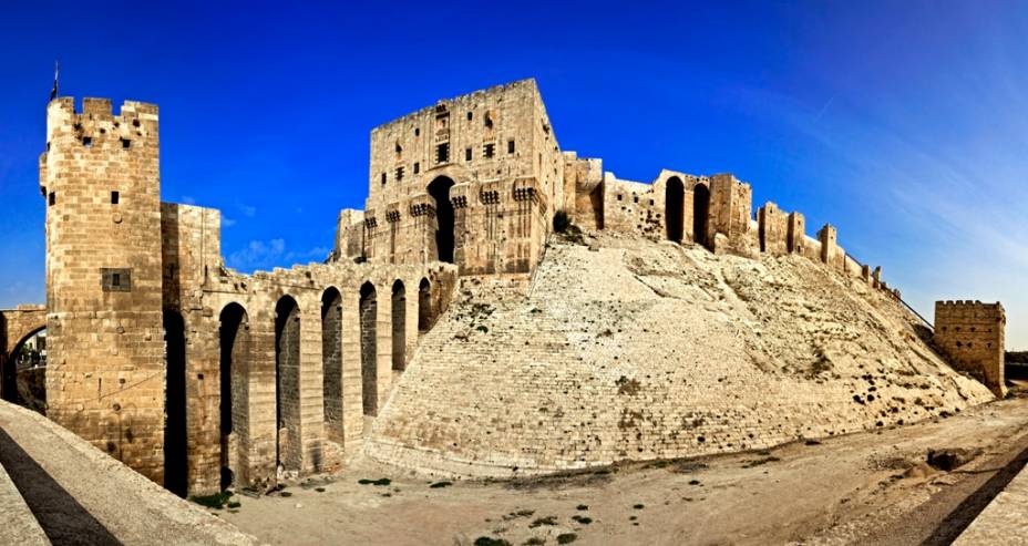 <strong>Cidadela de Aleppo, Síria</strong> A cidadela fortificada de Aleppo é uma típica fortificação medieval, com fosso, ponte de acesso protegida por torres e ameias defensivas. Foi construída originalmente pela dinastia aiúbida, na virada do século 13, e sofreu diversos ataques e ampliações nos séculos subsequentes. Outro forte igualmente vistoso na região é o Krak de Chevaliers, erguido pelos cruzados e capturado pelos mamelucos em 1271 <strong>Cidadela de Aleppo, Síria</strong> A cidadela fortificada de Aleppo é uma típica fortificação medieval, com fosso, ponte de acesso protegida por torres e ameias defensivas. Foi construída originalmente pela dinastia aiúbida, na virada do século 13, e sofreu diversos ataques e ampliações nos séculos subsequentes. Outro forte igualmente vistoso na região é o Krak de Chevaliers, erguido pelos cruzados e capturado pelos mamelucos em 1271
