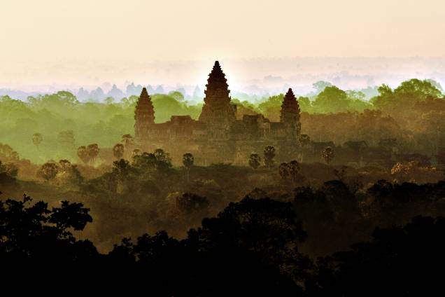 <strong>Angkor: uma imensidão de construções estonteantes</strong>Angkor se apresenta aos visitantes como um vasto território de floresta tropical com templos e pontes de pedra monumentais e maravilhosos no meio do caminho. Em seu auge, Angkor ocupava uma área maior do que a de Paris atual, e seus templos usaram muito mais pedras do que todas as estruturas egípcias juntas! Angkor Wat, na foto, é a maior estrutura religiosa do mundo <strong>Angkor: uma imensidão de construções estonteantes</strong>Angkor se apresenta aos visitantes como um vasto território de floresta tropical com templos e pontes de pedra monumentais e maravilhosos no meio do caminho. Em seu auge, Angkor ocupava uma área maior do que a de Paris atual, e seus templos usaram muito mais pedras do que todas as estruturas egípcias juntas! Angkor Wat, na foto, é a maior estrutura religiosa do mundo