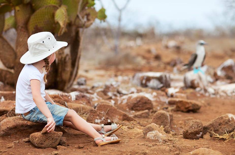 Menina observa pássaro na ilha de Galápagos, Equador Menina observa pássaro na ilha de Galápagos, Equador