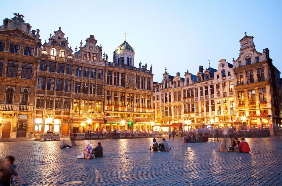 <a href="https://viajeaqui.abril.com.br/estabelecimentos/belgica-bruxelas-atracao-grand-place" rel="Grand-Place – Bruxelas – Bélgica" target="_blank"><strong>Grand-Place – Bruxelas – Bélgica</strong></a><a href="https://viajeaqui.abril.com.br/estabelecimentos/belgica-bruxelas-atracao-grand-place" rel="Grand-Place – Bruxelas – Bélgica" target="_blank"><strong> </strong></a>    Com a agulha da prefeitura dominando o entorno, a Grand Place de Bruxelas é o centro da vida comercial e cívica da cidade a quase mil anos. A combinação de vários estilos arquitetônicos que decoram as casas das guildas e sua rica história lhe valeram o título de Patrimônio da Humanidade pela Unesco. As poderosas guildas comerciais belgas mantinham suas sedes na praça – elas fecharam no século 18 e suas belas casas entrariam em acelerado processo de deterioração até voltarem a ser restauradas décadas mais tarde.    Com 96 metros de altura, o prédio mais imponente é o da Prefeitura, construído entre 1402 e 1455. É possível fazer uma visita guiada por dentro do lugar, repleto de objetos de arte. Outro prédio famoso que cerca a Grand Place é o da Casa do Rei, também do século 15, onde fica o Museu de Bruxelas. Quem não estiver afim de andar, pode simplesmente parar em um café e apreciar o visual comendo um waffle típico belga. Durante a noite a praça fica toda iluminada e ainda mais bonita. Todo ano par, no mês de agosto, a Grand Place é coberta com um tapete de flores que chega a ter 500 mil plantas!