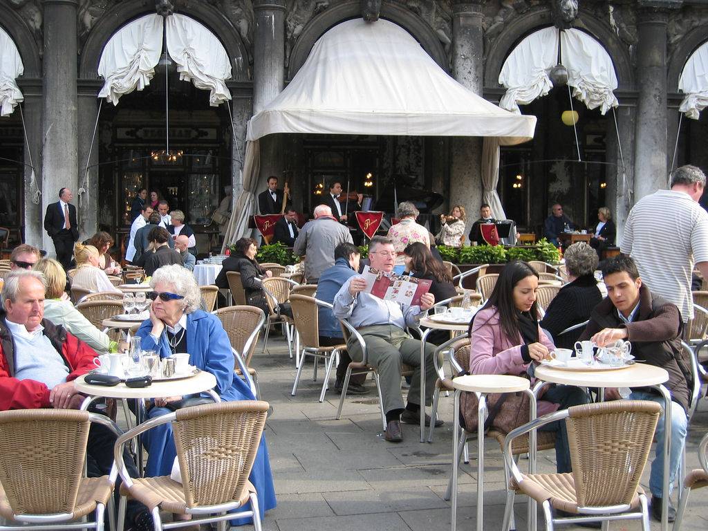 <strong>Caffè Florian</strong>, <strong>Veneza</strong><br />Entre os mais tradicionais da Europa, difícil concorrer com o <a href="https://viajeaqui.abril.com.br/estabelecimentos/italia-veneza-restaurante-caffe-florian" rel="Café Florian" target="_blank"><strong>Caffè Florian</strong></a> no item localização: Piazza San Marco, em <a href="https://viajeaqui.abril.com.br/cidades/italia-veneza" rel="Veneza" target="_blank"><strong>Veneza</strong></a>. Fundado em 1720, o que faz dele a mais antiga cafeteria da Itália, é tão icônico e visitado quanto a Basílica di San Marco! Chamado inicialmente <em>Caffè alla Venezia Trionfante </em>(Café da Veneza triunfante) logo recebeu o nome atual, referência ao seu proprietário, Floriano Francesconi. De suas mesas ao ar livre, famosos e turistas comuns curtem o visual enquanto saboreiam um <em>vero espresso</em> (expresso verdadeiro).<br /><br />A galeria de celebridades que se sentaram às suas mesas inclui Carlo Goldoni, Goethe, Marcel Proust, Lord Byron e Charles Dickens. Um de seus mais assíduos frequentadores, o sedutor Casanova tinha um motivo muito forte para fazê-lo: Floriano Francesconi havia conseguido uma licença especial do Doge de Veneza autorizando a entrada de mulheres neste domínio tipicamente masculino, permitindo-lhe assim conhecer e escolher suas próximas conquistas. Este fato é comemorado, com uma coleção de joias artesanais típicas da ourivesaria veneziana, produzidas e vendidas no próprio café.<br /><br />O Florian mantém o luxo em seu interior, dividido em várias salas, batizadas com nomes simbólicos: <em>Sala degli Uomini Illustri</em> (Sala dos homens ilustres), <em>Sala del Senato</em> (Sala do Senado) e <em>Sala degli Specchi</em> (sala dos espelhos), entre outras. Atualmente estas salas são um espaço dedicado à arte contemporânea e a outras manifestações culturais. Uma orquestra permanente se encarrega do fundo musical. Seus preços estão à altura de seu status <strong>Caffè Florian</strong>, <strong>Veneza</strong><br />Entre os mais tradicionais da Europa, difícil concorrer com o <a href="https://viajeaqui.abril.com.br/estabelecimentos/italia-veneza-restaurante-caffe-florian" rel="Café Florian" target="_blank"><strong>Caffè Florian</strong></a> no item localização: Piazza San Marco, em <a href="https://viajeaqui.abril.com.br/cidades/italia-veneza" rel="Veneza" target="_blank"><strong>Veneza</strong></a>. Fundado em 1720, o que faz dele a mais antiga cafeteria da Itália, é tão icônico e visitado quanto a Basílica di San Marco! Chamado inicialmente <em>Caffè alla Venezia Trionfante </em>(Café da Veneza triunfante) logo recebeu o nome atual, referência ao seu proprietário, Floriano Francesconi. De suas mesas ao ar livre, famosos e turistas comuns curtem o visual enquanto saboreiam um <em>vero espresso</em> (expresso verdadeiro).<br /><br />A galeria de celebridades que se sentaram às suas mesas inclui Carlo Goldoni, Goethe, Marcel Proust, Lord Byron e Charles Dickens. Um de seus mais assíduos frequentadores, o sedutor Casanova tinha um motivo muito forte para fazê-lo: Floriano Francesconi havia conseguido uma licença especial do Doge de Veneza autorizando a entrada de mulheres neste domínio tipicamente masculino, permitindo-lhe assim conhecer e escolher suas próximas conquistas. Este fato é comemorado, com uma coleção de joias artesanais típicas da ourivesaria veneziana, produzidas e vendidas no próprio café.<br /><br />O Florian mantém o luxo em seu interior, dividido em várias salas, batizadas com nomes simbólicos: <em>Sala degli Uomini Illustri</em> (Sala dos homens ilustres), <em>Sala del Senato</em> (Sala do Senado) e <em>Sala degli Specchi</em> (sala dos espelhos), entre outras. Atualmente estas salas são um espaço dedicado à arte contemporânea e a outras manifestações culturais. Uma orquestra permanente se encarrega do fundo musical. Seus preços estão à altura de seu status