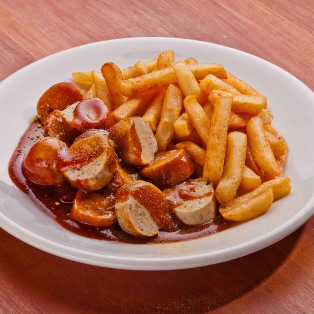 Currywurst, fast-food alemão, com batatas fritas e salsicha de porco fatiada, coberta por catchup ao curry