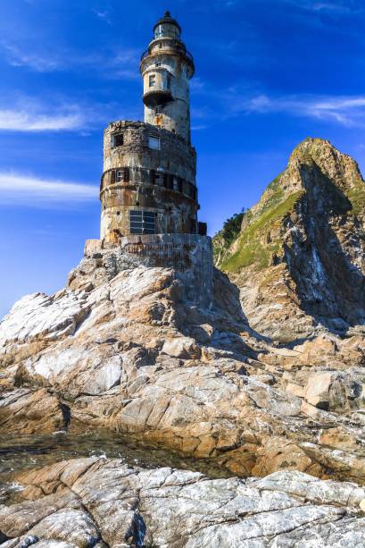 <strong>Farol Aniva Cape, Ilha Sakhalin, <a href="https://viajeaqui.abril.com.br/paises/russia" rel="Rússia" target="_blank">Rússia</a></strong>Com 948 km de extensão, a Ilha de Sacalina faz fronteira com o <a href="https://viajeaqui.abril.com.br/paises/japao" rel="Japão" target="_blank">Japão</a> e é demarcada por uma cadeia de faróis em praias desabitadas do Império Russo, construídos com o intuito de orientar navegadores do antigo Partido Comunista da União Soviética. Isolado de áreas povoadas, o Farol Aniva fez parte dessas construções erguidas com uma grande importância histórica para o país, mas que hoje encontram-se abandonados pela falta de utilidade. Abandonado depois do colapso da União Soviética, hoje o farol encontra-se em ruínas e sofre com a ação de vândalos. Mas quem se arrisca por seu interior e pelo aspecto sinistro de suas paredes descascadas e janelas quebradas pode, inclusive, ver documentos esquecidos durante o período e ter uma visão privilegiada do mar