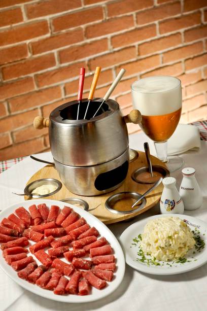 <strong>Konstanz</strong><br />  O cardápio do restaurante alemão reúne diversas versões da fondue: queijo (R$ 92), carne ao vinho (R$ 99), alemã (R$ 97), carpaccio, ao consumê ou ao vinho (R$ 99), salmão ao consume (R$ 110) e chocolate (R$70). Todas servem duas pessoas.<br />  <br />  <strong>Onde:</strong> Avenida Aratãs, 713, Moema, São Paulo – Tel. (11) 5543-4813, <a href="https://www.konstanz.com.br" rel="www.konstanz.com.br">www.konstanz.com.br</a><br />  <strong>Horário de funcionamento:</strong> Segunda a sábado, das 12h à 1h. Domingo, das 12h às 18h<br />  <br />