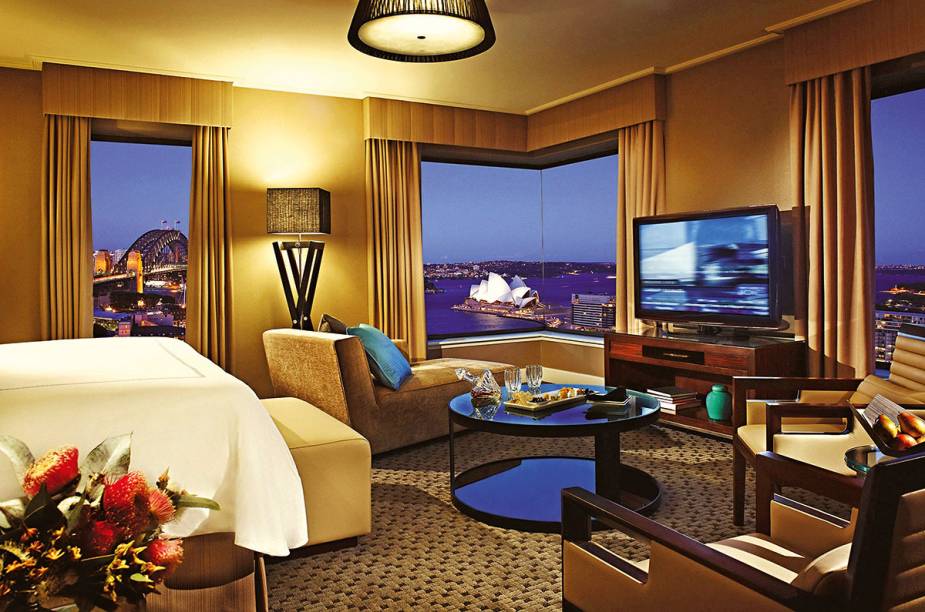 A TV da Junior Suite do <a href="https://www.booking.com/hotel/au/four-seasons-sydney.pt-br.html?aid=332455&sid=d98f25c4d6d5f89238aebe98e11a09ba&dest_id=-1603135&dest_type=city&group_adults=2&group_children=0&hapos=1&hpos=1&no_rooms=1&sr_order=popularity&srepoch=1569951938&srpvid=56a97ce059320025&ucfs=1&from=searchresults;highlight_room=#hotelTmpl" target="_blank" rel="noopener"><strong>Four Seasons Sydney</strong></a> pode até ser full HD, ter a maior seleção de canais a cabo ever, som Dolby, o diabo, mas o que de fato emociona, prende e hipnotiza é a vista das janelas para nada menos do que a <a href="https://beta-develop.viagemeturismo.abril.com.br/atracao/sydney-opera-house/" target="_blank" rel="noopener">Ópera</a> e a ponte Harbour, dois supercartões-postais da <a href="https://beta-develop.viagemeturismo.abril.com.br/paises/australia-2/" target="_blank" rel="noopener">Austrália</a>. O arrebatamento é tamanho que você até esquece que a mobília dos quartos está um pouco cansada e que o wi-fi é pago.