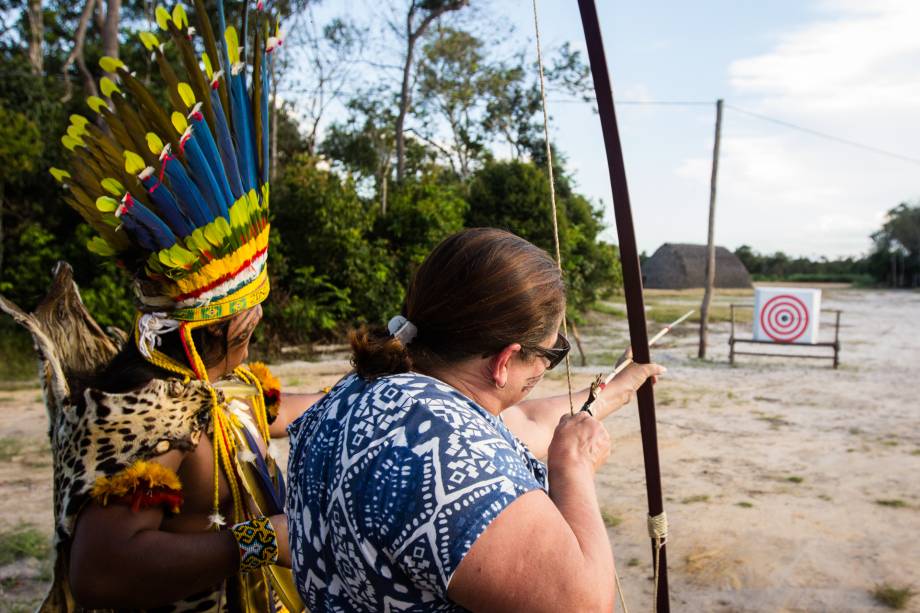 Além de vestir-se, pintar-se e comer como os indígenas, os turistas também têm aulas de arco-e-flecha tradicional da etnia. Além de vestir-se, pintar-se e comer como os indígenas, os turistas também têm aulas de arco-e-flecha tradicional da etnia.