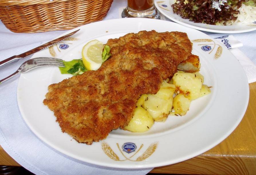 <strong>Schnitzel, <a href="https://viajeaqui.abril.com.br/paises/austria" rel="Áustria" target="_blank">Áustria</a></strong><br />  Muito popular em países do Centro da Europa, principalmente <a href="https://viajeaqui.abril.com.br/paises/suica" rel="Suíça" target="_blank">Suíça</a>, <a href="https://viajeaqui.abril.com.br/paises/republica-tcheca" rel="República Tcheca " target="_blank">República Tcheca </a>e <a href="https://viajeaqui.abril.com.br/paises/alemanha" rel="Alemanha" target="_blank">Alemanha</a>, este <strong>prato austríaco</strong> é um carne batida (normalmente porco), empanada em farinha de rosca e frita em óleo. Suas guarnições mais usuais são batatas (fritas, cozidas ou em purê) 