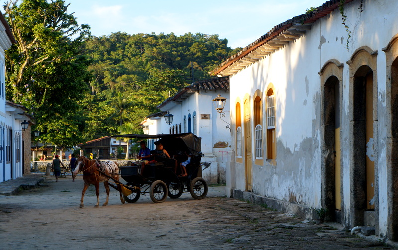 <strong>Paraty (RJ)  </strong> Uma cidade colonial cujo centro foi completamente tombado como Patrimônio da Humanidade pela UNESCO que fica à beira do mar e ao pé da serra. Paraty tem de tudo: charmosas ruas de calçamento de pedra, edifícios históricos e lojinhas interessantes, boa oferta de restaurantes, uma agenda cultural efervescente, natureza exuberante, trilhas de diversos níveis de dificuldade, cachoeiras escondidas e cachoeiras acessíveis por transporte público e ainda praias belíssimas a menos de uma hora de passeio de barco. Os melhores hoteis e pousadas ficam dentro do Centro Histórico, em casarões antigos com pátios internos bem arborizados, quartos amplos e café da manhã que vai até tarde. <a href="https://www.booking.com/searchresults.pt-br.html?aid=332455&sid=605c56653290b80351df808102ac423d&sb=1&src=index&src_elem=sb&error_url=https%3A%2F%2Fwww.booking.com%2Findex.pt-br.html%3Faid%3D332455%3Bsid%3D605c56653290b80351df808102ac423d%3Bsb_price_type%3Dtotal%26%3B&ss=Paraty%2C+Estado+do+Rio+de+Janeiro%2C+Brasil&checkin_monthday=&checkin_month=&checkin_year=&checkout_monthday=&checkout_month=&checkout_year=&no_rooms=1&group_adults=2&group_children=0&b_h4u_keep_filters=&from_sf=1&ss_raw=PAraty&ac_position=0&ac_langcode=xb&dest_id=-659504&dest_type=city&place_id_lat=-23.217944&place_id_lon=-44.712917&search_pageview_id=7219849619730182&search_selected=true&search_pageview_id=7219849619730182&ac_suggestion_list_length=5&ac_suggestion_theme_list_length=0" target="_blank" rel="noopener"><em>Busque hospedagens em Paraty</em></a>