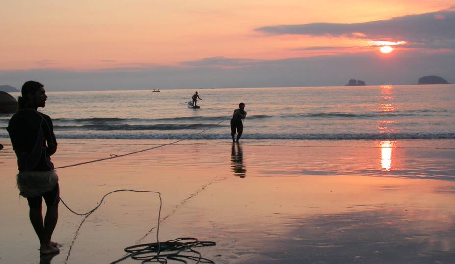 Pôr do sol na <a href="https://viajeaqui.abril.com.br/estabelecimentos/br-sp-ubatuba-atracao-praia-picinguaba" rel="praia Picinguaba" target="_blank">praia Picinguaba</a>, em <a href="https://viajeaqui.abril.com.br/cidades/br-sp-ubatuba" rel="Ubatuba (SP)" target="_blank">Ubatuba</a>; quase não há faixa de areia por aqui e, para quem quiser curtir a paisagem, há um barzinho muito bem localizado no canto esquerdo