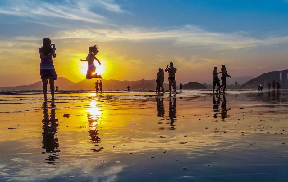 Banhistas apreciam o pôr do sol na orla da cidade de Santos (SP)