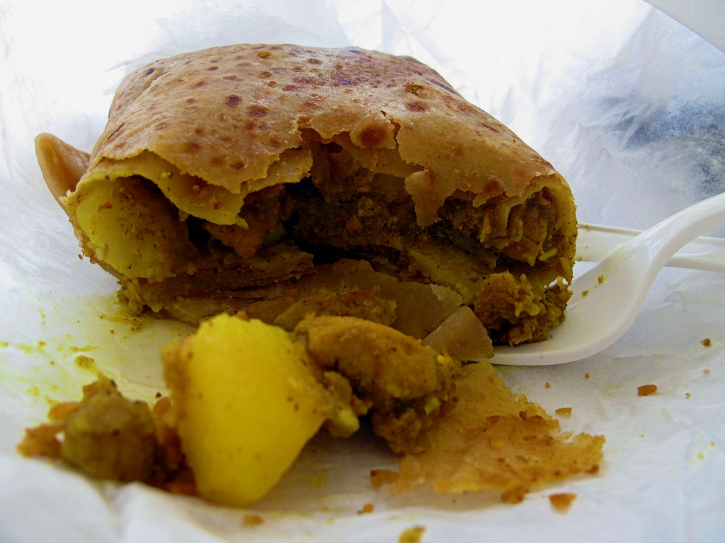 <strong>Chicken Roti, Trinidad e Tobago</strong><br /><em>Roti</em>? Mas isso não é um prato indiano? Sim, caros, num pequeno e próspero arquipélago grudado na costa venezuelana vive um povo que é uma doida mistura de negros, britânicos e indianos. Estes últimos são mais de 40% da população e trouxeram para o país parte de sua cultura e, é claro, gastronomia.O mais simbólico produto deste movimento é uma massaroca de frango com curry, envelopada numa fina folha de pão, o <em>roti</em>. Você encontrará a condimentada iguaria em disputadas lojinhas espalhadas por todo o país. <strong>Chicken Roti, Trinidad e Tobago</strong><br /><em>Roti</em>? Mas isso não é um prato indiano? Sim, caros, num pequeno e próspero arquipélago grudado na costa venezuelana vive um povo que é uma doida mistura de negros, britânicos e indianos. Estes últimos são mais de 40% da população e trouxeram para o país parte de sua cultura e, é claro, gastronomia.O mais simbólico produto deste movimento é uma massaroca de frango com curry, envelopada numa fina folha de pão, o <em>roti</em>. Você encontrará a condimentada iguaria em disputadas lojinhas espalhadas por todo o país.