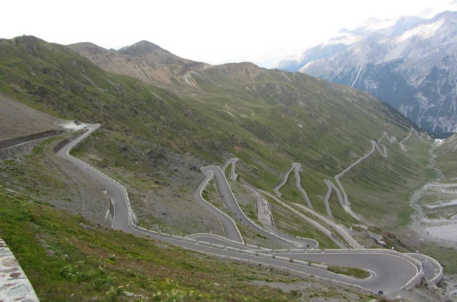 Ela sai de Davos, na Su&iacute;&ccedil;a, e vai at&eacute; Stelvio, na It&aacute;lia. O Passo Stelvio tem 60 curvas ao longo de 144 quil&ocirc;metros, e curvas beeeem estreitas. Enquanto tenta n&atilde;o derrapar, o motorista pode exercitar a vis&atilde;o perif&eacute;rica espiando uma paisagem alpina absurdamente bonita, que vale cada viradinha no volante. A estrada passa por dentro do Parque Nacional de Stelvio, ao lado do lago di Livigno (felizmente em um trecho de 10 quil&ocirc;metros em linha reta), pertinho de vacas balan&ccedil;ando guizos. Tudo a prosaicos 2 757 metros de altura.