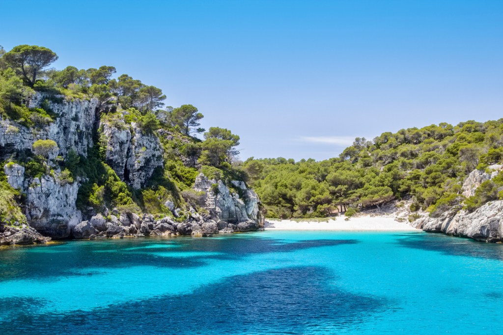 <strong>Cala Macarelleta, <a href="https://viajeaqui.abril.com.br/cidades/espanha-menorca" rel="Menorca" target="_self">Menorca</a>, <a href="https://viajeaqui.abril.com.br/paises/espanha" rel="Espanha" target="_self">Espanha</a></strong>                    O acesso &agrave; praia &eacute; mais restrito, feito de carro e com uma trilha de dez minutos que antecede sua bela vis&atilde;o. No entanto, os turistas s&atilde;o un&acirc;nimes quanto ao cen&aacute;rio: um verdadeiro para&iacute;so de areia branca e &aacute;gua turquesa. Tamb&eacute;m h&aacute; op&ccedil;&otilde;es de passeios de barco, perfeitos para casais em lua de mel                    <em><a href="https://www.booking.com/region/es/menorca.pt-br.html?sid=5b28d827ef00573fdd3b49a282e323ef;dcid=4aid=332455&label=viagemabril-as-mais-belas-praias-do-mediterraneo" rel="Veja pre&ccedil;os de hot&eacute;is em Menorca no Booking.com" target="_blank">Veja pre&ccedil;os de hot&eacute;is em Menorca no Booking.com</a></em>