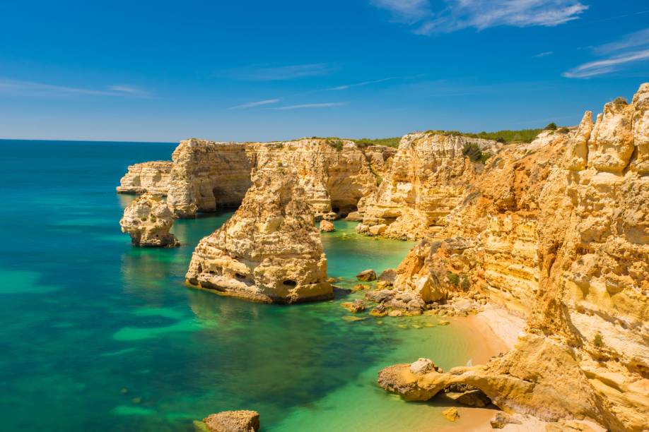 <strong>Praia da Marinha, Algarve, <a href="https://viajeaqui.abril.com.br/paises/portugal" rel="Portugal" target="_self">Portugal</a></strong> O título não é brincadeira: é uma das mais belas e emblemáticas praias do país, além de já ter sido eleita pelo Guia Michelin como uma das cem praias mais bonitas do mundo. Sua encosta é formada por falésias, marcando a beleza de águas cristalinas perfeitas para mergulho. Seu acesso é feito por uma escadaria, de onde se pode observar a vegetação de tomilhos silvestres <em><a href="https://www.booking.com/city/pt/carvoeiro.pt-br.html?sid=5b28d827ef00573fdd3b49a282e323ef;dcid=1?aid=332455&label=viagemabril-as-mais-belas-praias-do-mediterraneo" rel="Veja preços de hotéis próximos à Praia da Marinha no Booking.com" target="_blank">Veja preços de hotéis próximos à Praia da Marinha no Booking.com</a></em> <strong>Praia da Marinha, Algarve, <a href="https://viajeaqui.abril.com.br/paises/portugal" rel="Portugal" target="_self">Portugal</a></strong> O título não é brincadeira: é uma das mais belas e emblemáticas praias do país, além de já ter sido eleita pelo Guia Michelin como uma das cem praias mais bonitas do mundo. Sua encosta é formada por falésias, marcando a beleza de águas cristalinas perfeitas para mergulho. Seu acesso é feito por uma escadaria, de onde se pode observar a vegetação de tomilhos silvestres <em><a href="https://www.booking.com/city/pt/carvoeiro.pt-br.html?sid=5b28d827ef00573fdd3b49a282e323ef;dcid=1?aid=332455&label=viagemabril-as-mais-belas-praias-do-mediterraneo" rel="Veja preços de hotéis próximos à Praia da Marinha no Booking.com" target="_blank">Veja preços de hotéis próximos à Praia da Marinha no Booking.com</a></em>