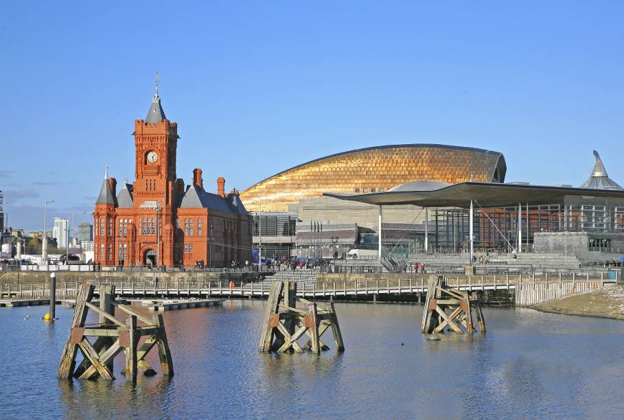 Uma das clássicas vistas da cidade de <strong>Cardiff</strong> é deste edifício de paredes vermelhas, no porto – construído inicialmente para atender as demandas portuárias, em 1897, hoje o prédio, apelidado carinhosamente de "Baby Big Ben", é um museu. Ao fundo, é possível ver o modernoso Millenium Stadium, outro símbolo local