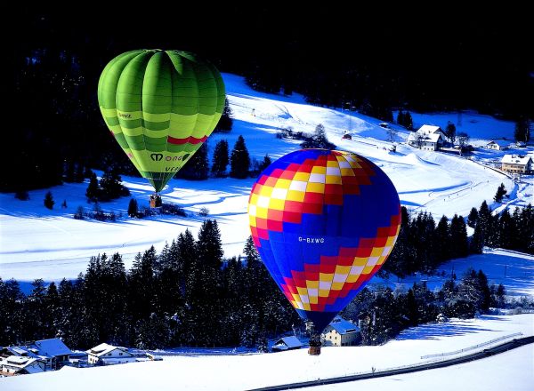 Balões se destacam na alva paisagem de Val Gardena . Na volta do passeio, substanciosos e suculentos pratos à base de batatas, carnes de caça e de porco, chucrute e cevada - testemunhos da influência dos vizinhos austríacos e suíços, esperam por você.