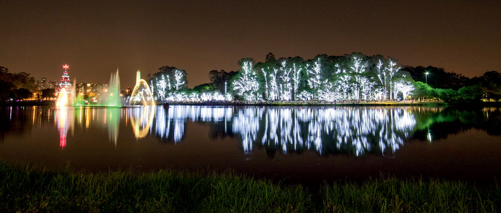 O Lago do Ibirapuera com suas &aacute;guas dan&ccedil;antes em vers&atilde;o natalina e a &aacute;rvore com a estrela a iluminar o caminho