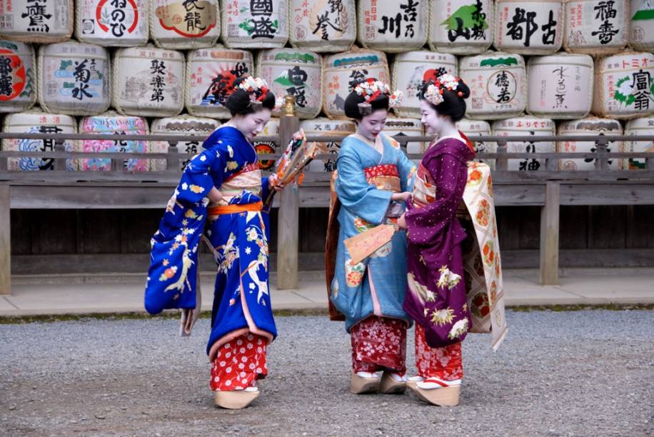 Aprendizes de geisha, conhecidas como maiko, vestem-se com seus coloridos kimonos no santuário Matsuo Taisha, em Kyoto. Ao fundo, tambores de sakê utilizados como oferendas. Aprendizes de geisha, conhecidas como maiko, vestem-se com seus coloridos kimonos no santuário Matsuo Taisha, em Kyoto. Ao fundo, tambores de sakê utilizados como oferendas.