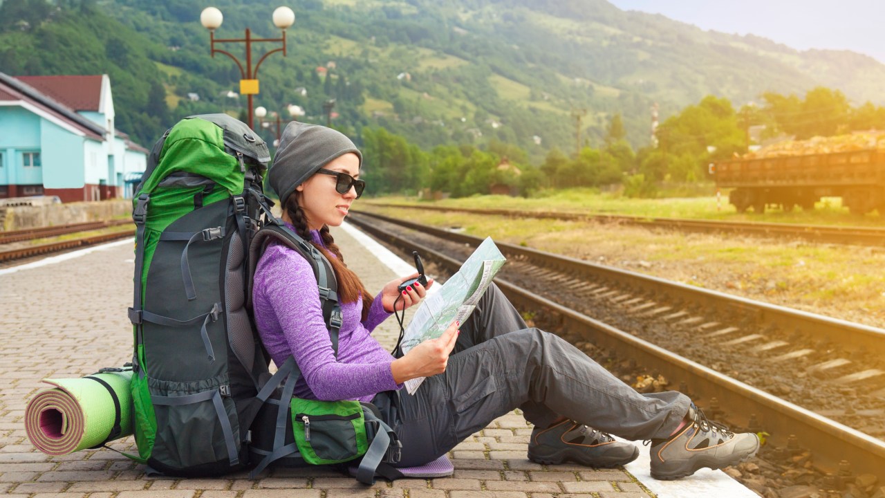 Girl hiker waiting train at the railway station