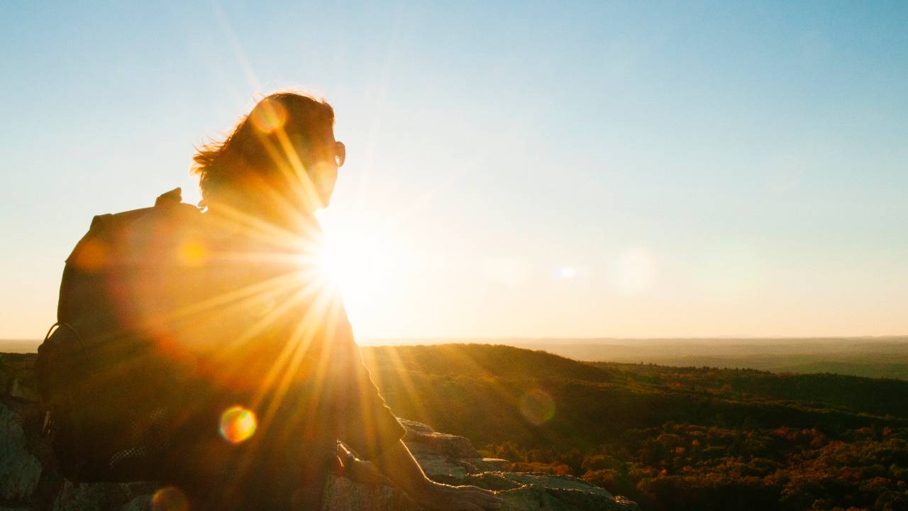 Mulher viajante observa paisagem ao pôr do sol