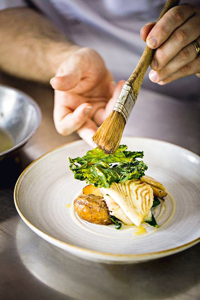 Prato do restaurante James Sommerin, em Penarth, perto de Cardiff, País de Gales Prato sofisticado de batata e frango sendo finalizado com uma pincelada do cozinheiro