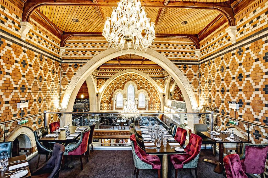 Restaurante Chapel 1877 em Cardiff, País de Gales O interior de uma capela totalmente reestruturada para servir como um restaurante de dois andares, com paredes de tijolos e lustres pendendo em diferentes lugares