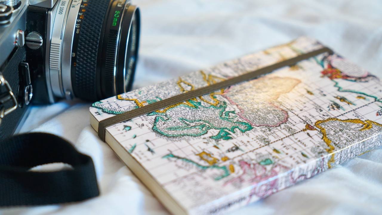 Diário de viagem e câmera fotográfica em cima de mapa
