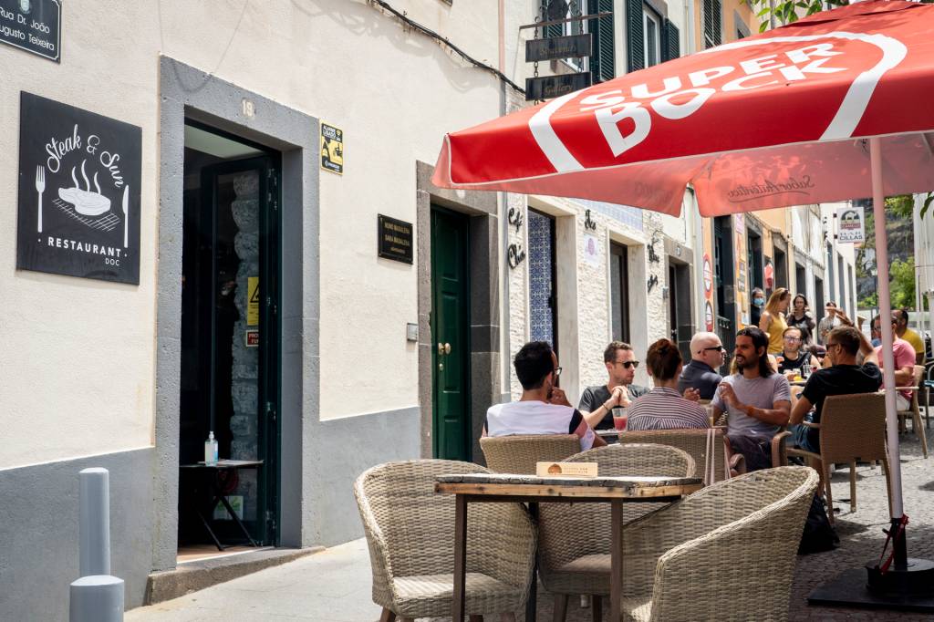 Restaurante com mesas ao ar livre debaixo de um guarda-sol vermelho