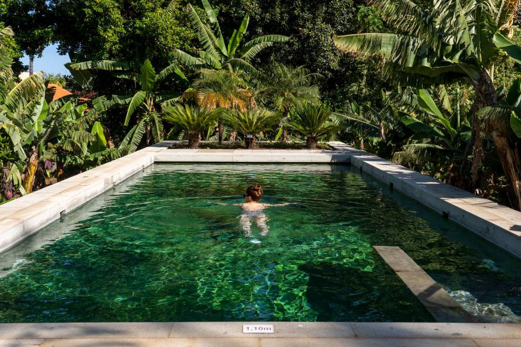 Mulher nadando em uma piscina cercada de bananeiras