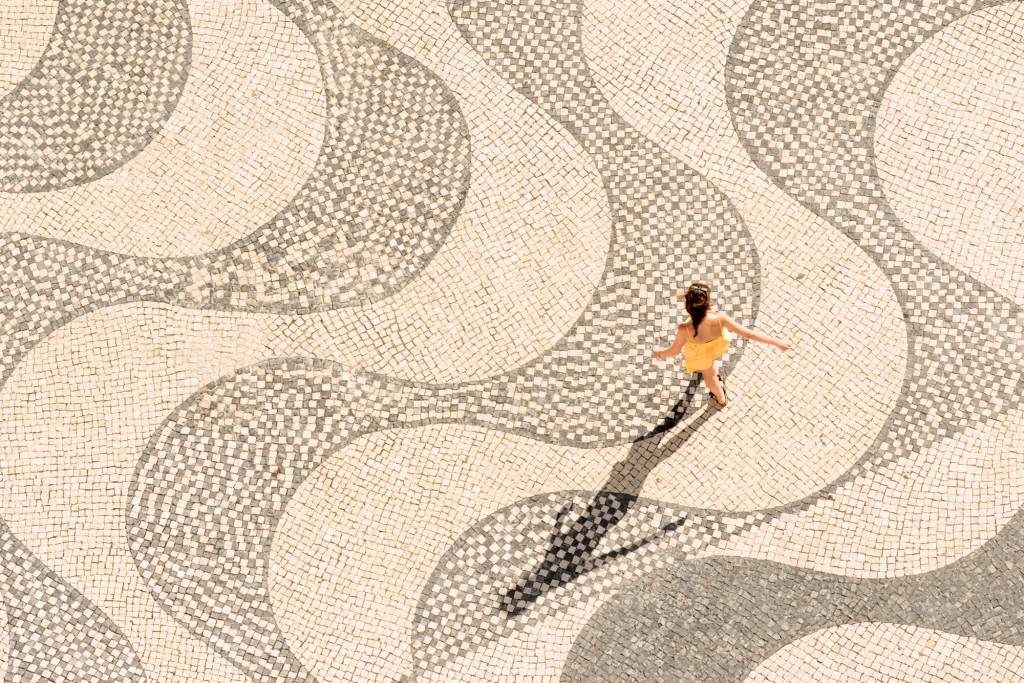 Belém_Pessoas_CalçadaPortuguesa_BrunoBarata-300 Menina de vestido amarelo anda de braços abertos sobre calçada portuguesa