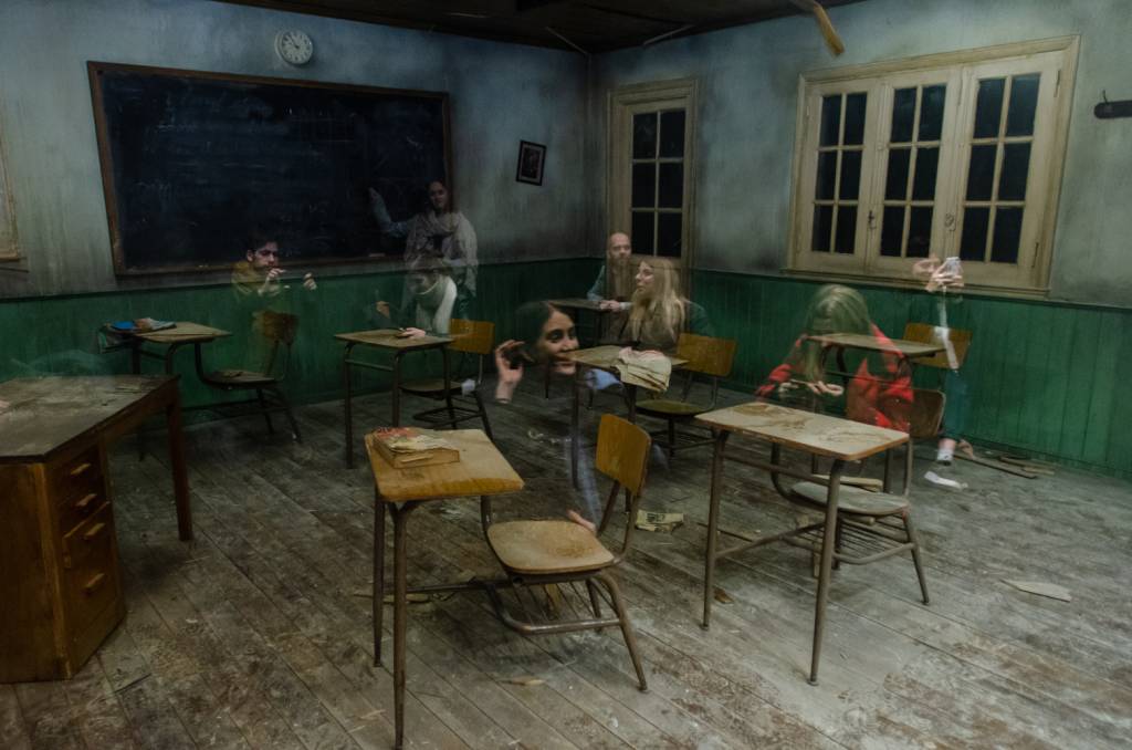A cena reproduzida causa a impress&atilde;o de que os visitantes s&atilde;o fantasmas em meio a uma sala de aula decadente