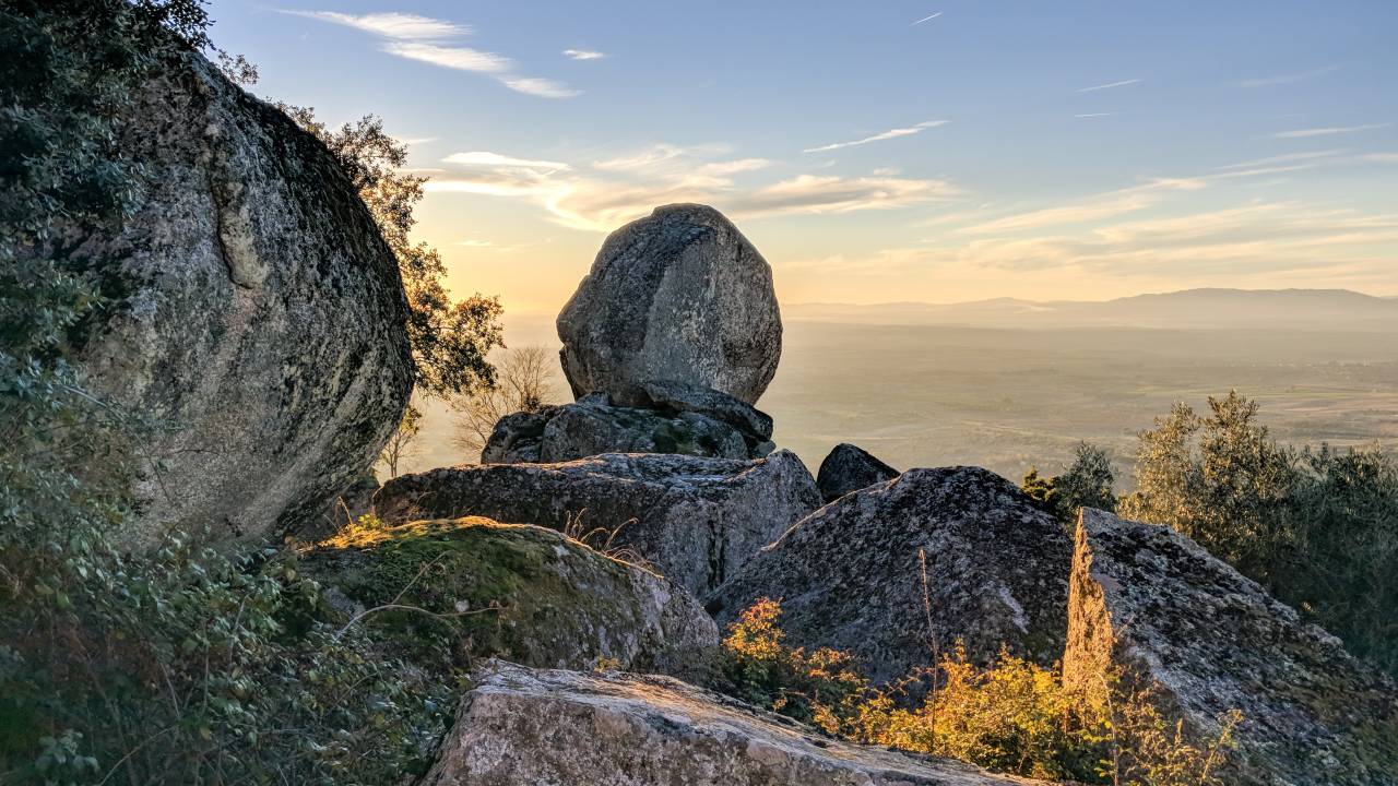 Enormes pedras no alto de uma montanha com céu azul e luz do pôr do sol