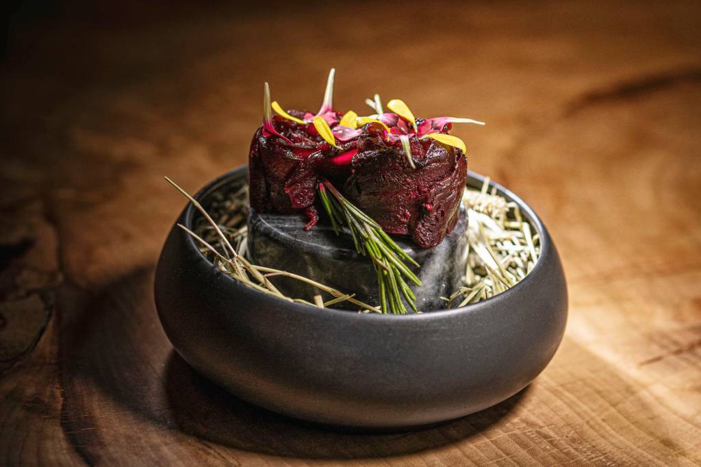 Pato redondo de cerâmica cinza com folhas de alecrim e dois bolinhos de beterraba decorados com flores