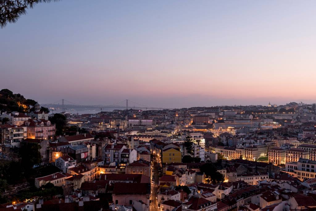 Graça_MiradouroDaGraça_BrunoBarata-258 O casario de Lisboa descendo a colina ao anoitecer, com o rio Tejo e a Ponte 25 de Abril ao fundo