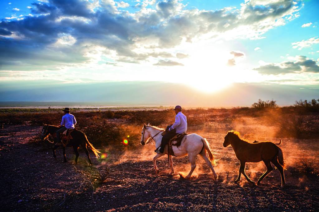 Cavalgada no Morro El Zorrito. Na imagem é possível ver algumas pessoas cavalgando sob o por do sol.